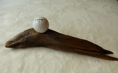 Slim piece of driftwood with a golf ball resting on top