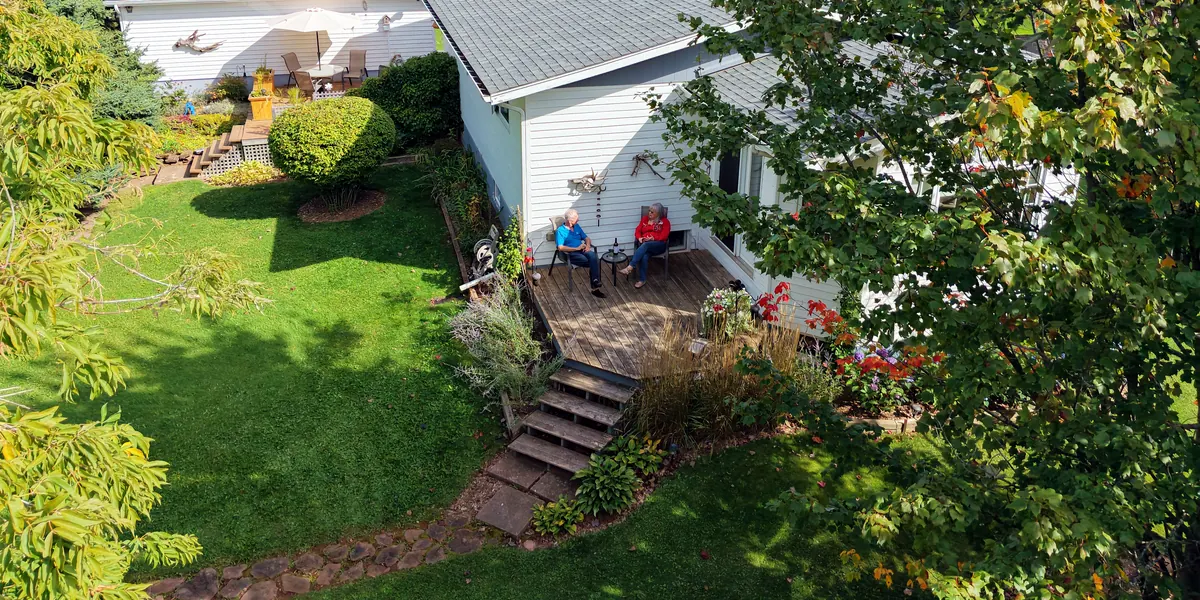 Brian and Beverly on the back deck, with the second deck and gardens beside the house